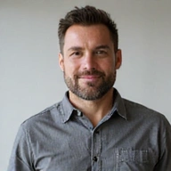 Portrait of a confident man with a beard, wearing a casual button-up shirt, looking friendly and knowledgeable.